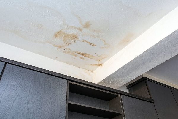 Gros plan d'une tache d'humidité sur un plafond blanc, signe typique d'une fuite de toiture.